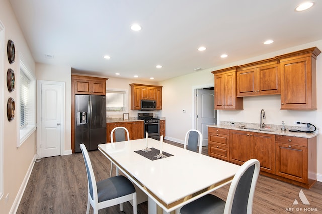 kitchen featuring sink, stainless steel appliances, hardwood / wood-style floors, an island with sink, and a breakfast bar