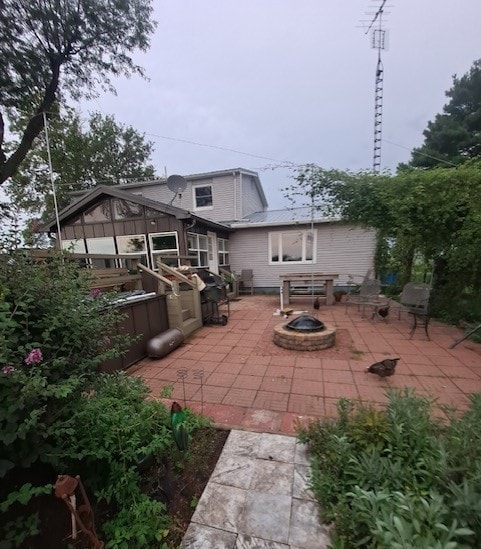 1522 E 7th Rd, Lostant, IL 61334 - rear view of property featuring an outdoor fire pit, a patio area, and metal roof