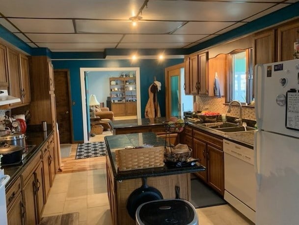1522 E 7th Rd, Lostant, IL 61334 - kitchen featuring dark countertops, white appliances, brown cabinetry, and a sink