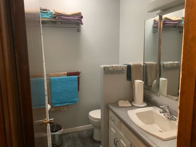 1522 E 7th Rd, Lostant, IL 61334 - bathroom featuring baseboards, wood finished floors, toilet, and vanity
