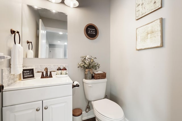 bathroom with decorative backsplash, toilet, and vanity