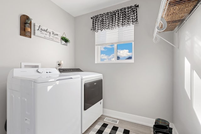 laundry area with washer and clothes dryer and light wood-type flooring