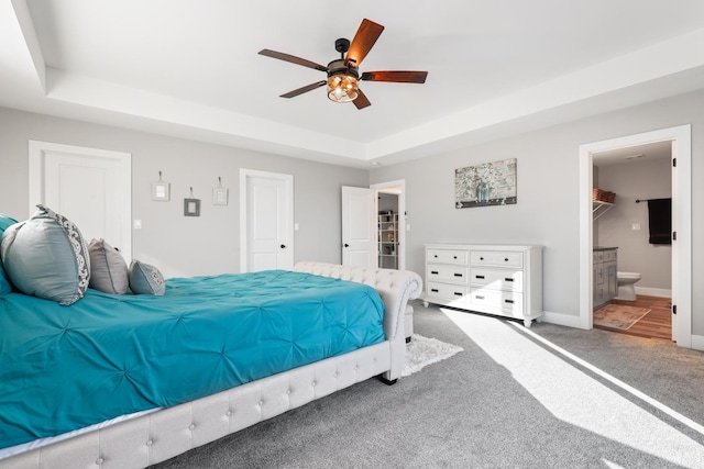 carpeted bedroom with ensuite bathroom, ceiling fan, a spacious closet, a tray ceiling, and a closet