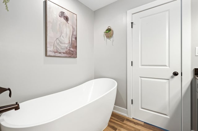 bathroom with a tub to relax in, hardwood / wood-style floors, and vanity