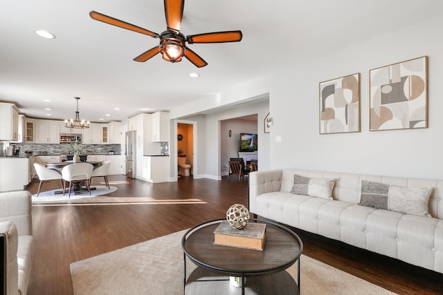 living room with ceiling fan with notable chandelier and dark hardwood / wood-style floors