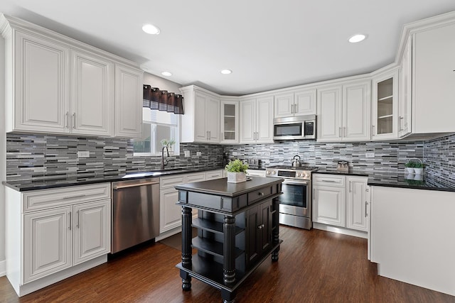 kitchen with tasteful backsplash, white cabinetry, dark wood-type flooring, and stainless steel appliances