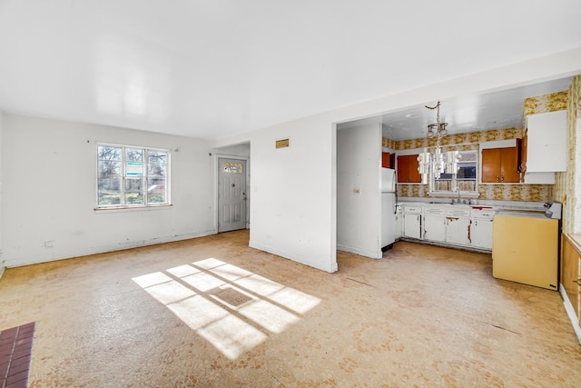 kitchen featuring stove, tasteful backsplash, pendant lighting, white cabinets, and white fridge