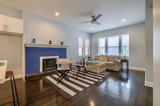 living room with a fireplace, dark hardwood / wood-style floors, and ceiling fan