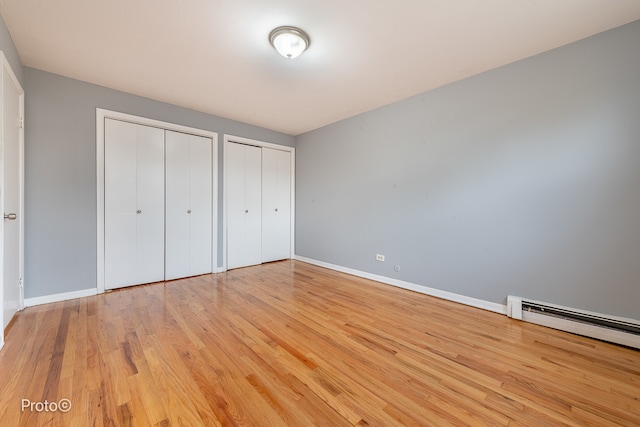 unfurnished bedroom featuring light hardwood / wood-style floors and two closets