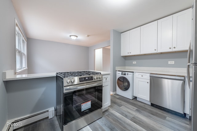 kitchen with appliances with stainless steel finishes, light wood-type flooring, a baseboard heating unit, washer / dryer, and white cabinetry