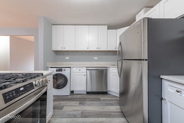 kitchen with washer / dryer, white cabinetry, stainless steel appliances, and light hardwood / wood-style flooring