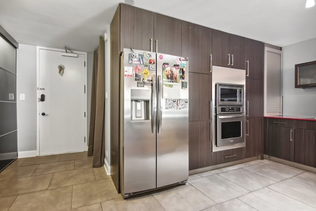 kitchen featuring dark brown cabinets, stainless steel fridge, and light tile patterned floors