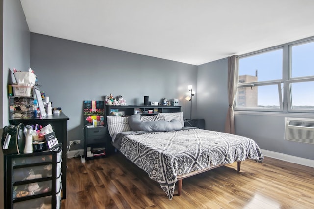 bedroom featuring wood-type flooring and an AC wall unit