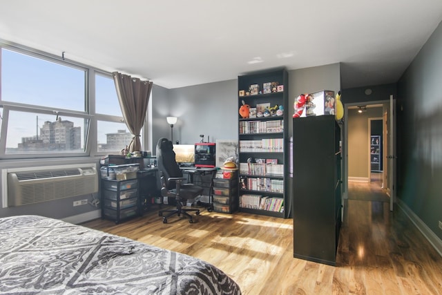 bedroom with hardwood / wood-style floors and a wall mounted AC