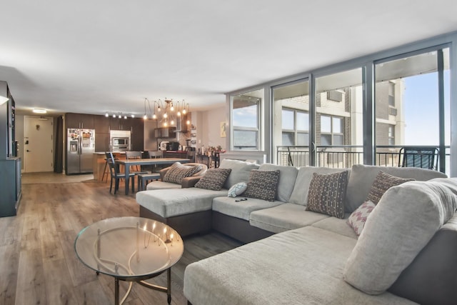 living room with a wall of windows, wood-type flooring, and a chandelier