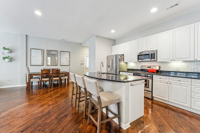 kitchen with appliances with stainless steel finishes, white cabinetry, and dark wood-type flooring