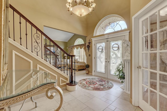 tiled foyer featuring an inviting chandelier, a high ceiling, and french doors