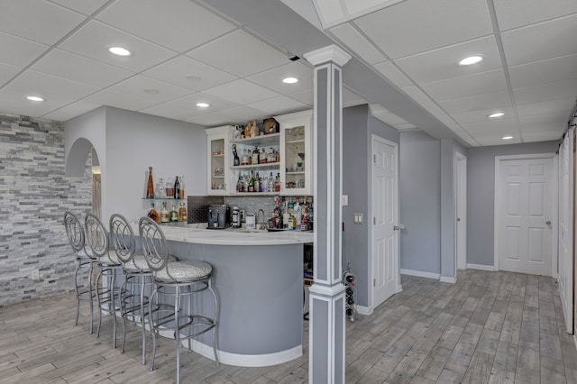 bar featuring white cabinets, a paneled ceiling, and light hardwood / wood-style floors