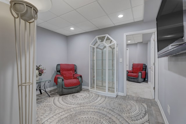 sitting room with hardwood / wood-style flooring and a drop ceiling