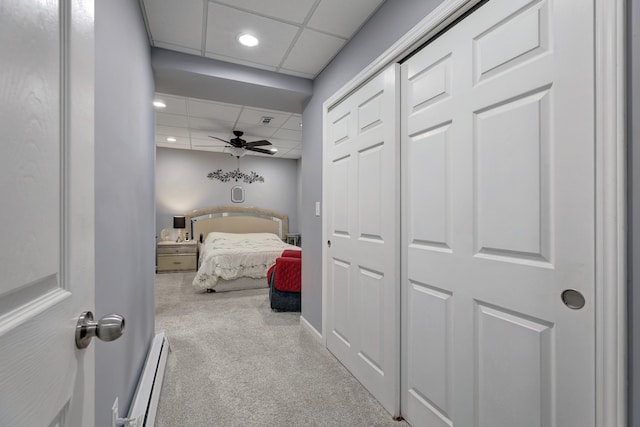 bedroom with a paneled ceiling, ceiling fan, light carpet, and a baseboard heating unit