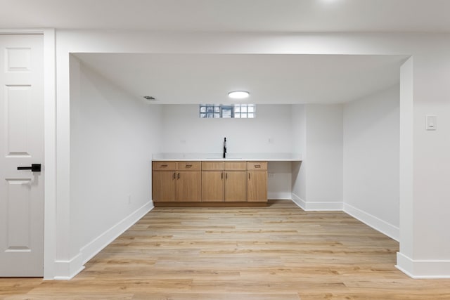 bar with light hardwood / wood-style flooring and sink