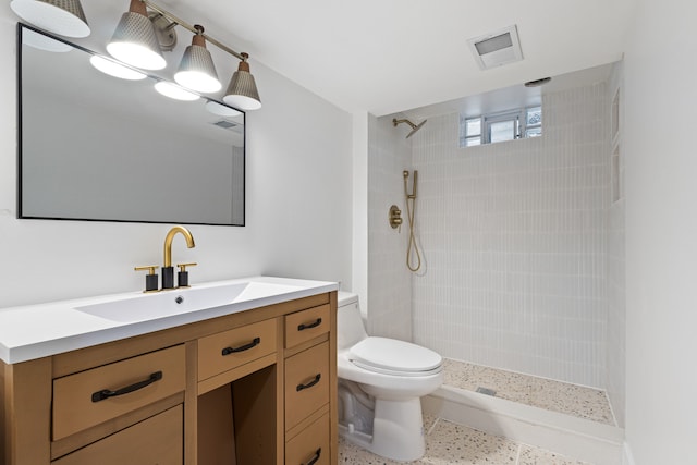 bathroom with vanity, toilet, and a tile shower