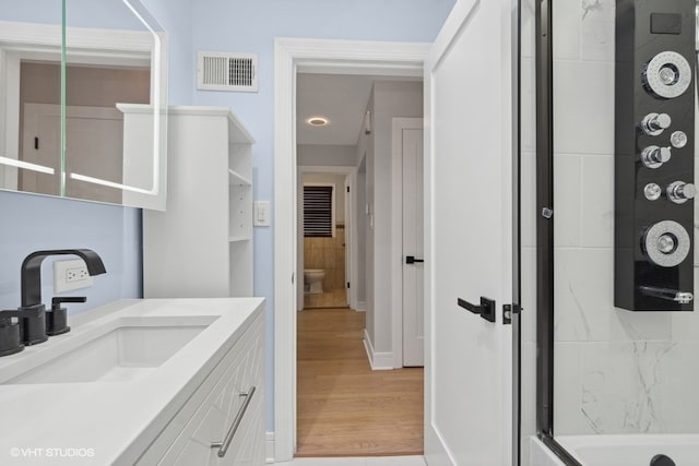 full bathroom with hardwood / wood-style floors, vanity, toilet, and combined bath / shower with glass door