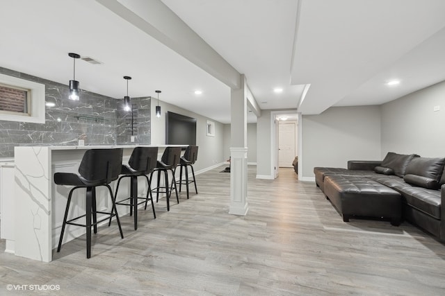 bar featuring white cabinets, decorative light fixtures, light wood-type flooring, and tasteful backsplash