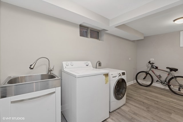 clothes washing area with independent washer and dryer, light wood-type flooring, and sink