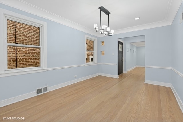 spare room featuring light hardwood / wood-style floors, ornamental molding, and an inviting chandelier