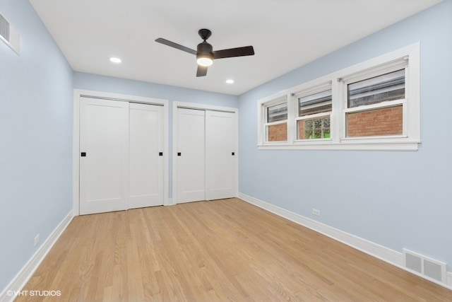 unfurnished bedroom featuring ceiling fan, light hardwood / wood-style flooring, and two closets