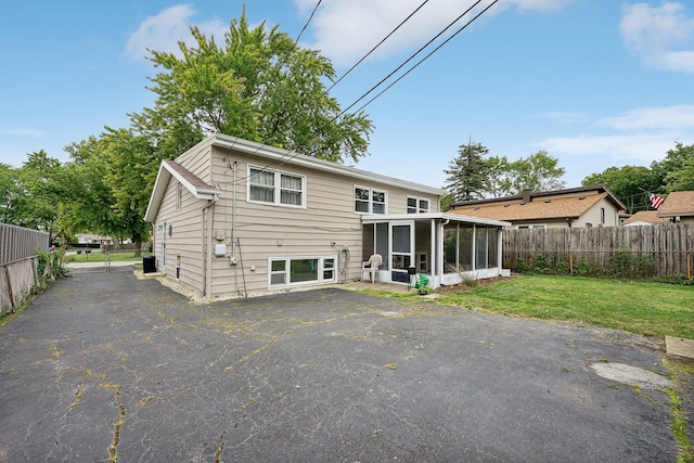 back of property with a sunroom and a yard