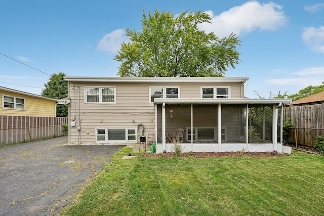 back of house featuring a sunroom and a lawn