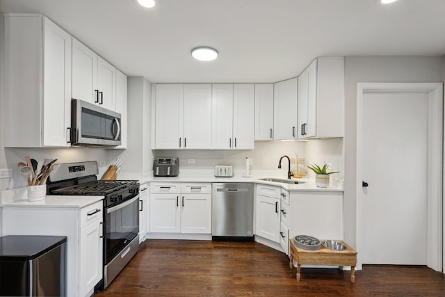 kitchen featuring white cabinetry, sink, dark wood-type flooring, and appliances with stainless steel finishes