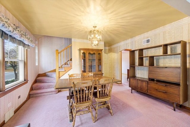 carpeted dining space with a chandelier and ornamental molding