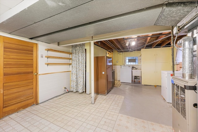 basement with stainless steel fridge, sink, and independent washer and dryer