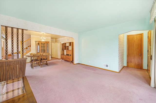 living room featuring carpet, crown molding, and a notable chandelier