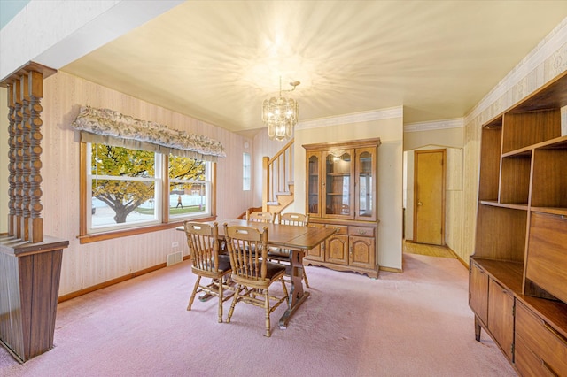 carpeted dining area with ornamental molding and an inviting chandelier