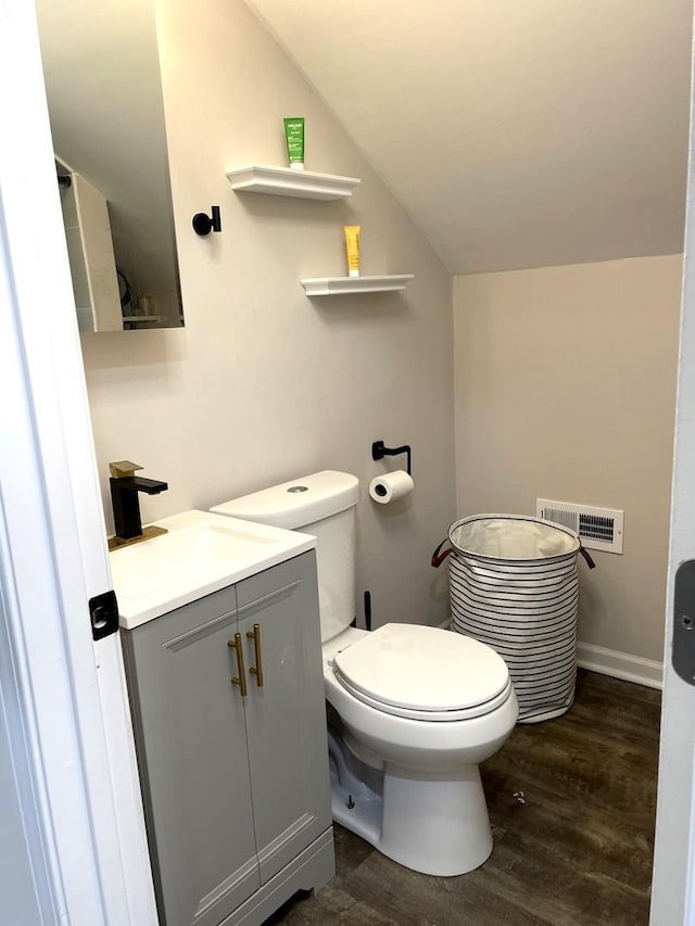 bathroom with vanity, hardwood / wood-style flooring, toilet, and lofted ceiling