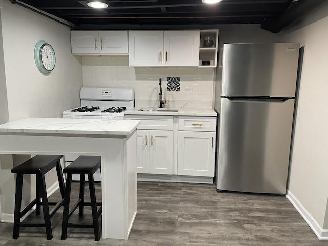 kitchen featuring sink, a breakfast bar area, dark hardwood / wood-style floors, white cabinetry, and stainless steel refrigerator