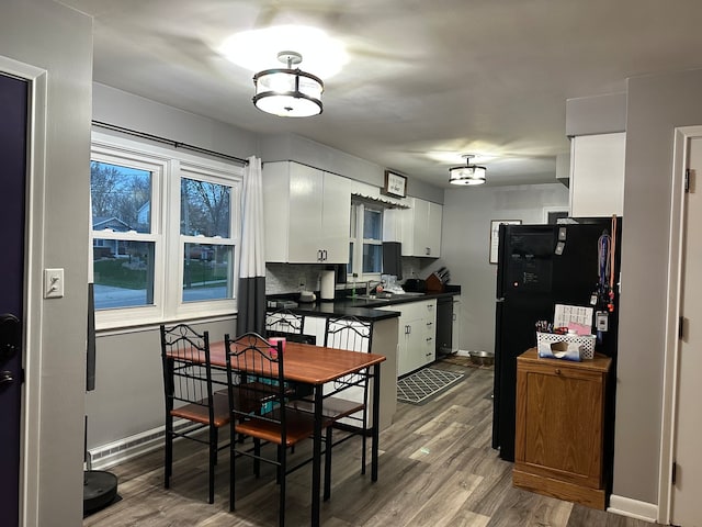 kitchen with tasteful backsplash, sink, white cabinets, and wood-type flooring