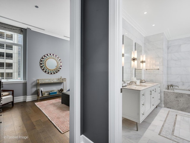 bathroom featuring crown molding, vanity, and tiled bath