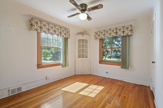 empty room with ceiling fan, hardwood / wood-style floors, and a healthy amount of sunlight