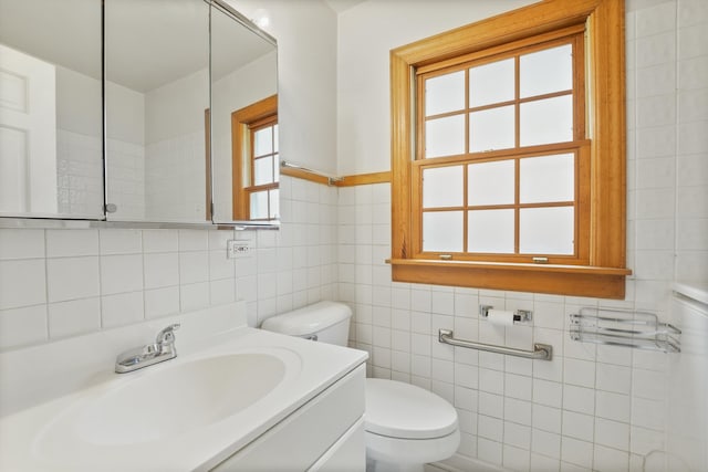 bathroom featuring vanity, toilet, and tile walls