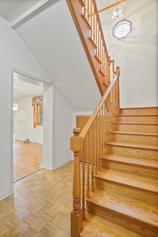 staircase featuring parquet floors, a chandelier, and lofted ceiling