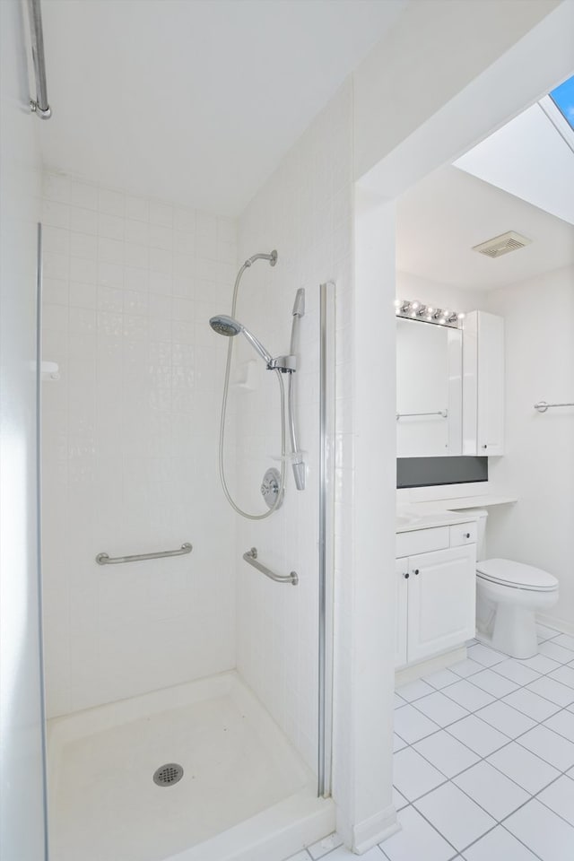 bathroom with tile patterned flooring, a tile shower, vanity, and toilet