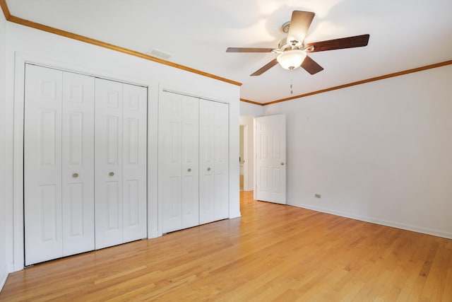 unfurnished bedroom featuring ceiling fan, light hardwood / wood-style floors, two closets, and ornamental molding