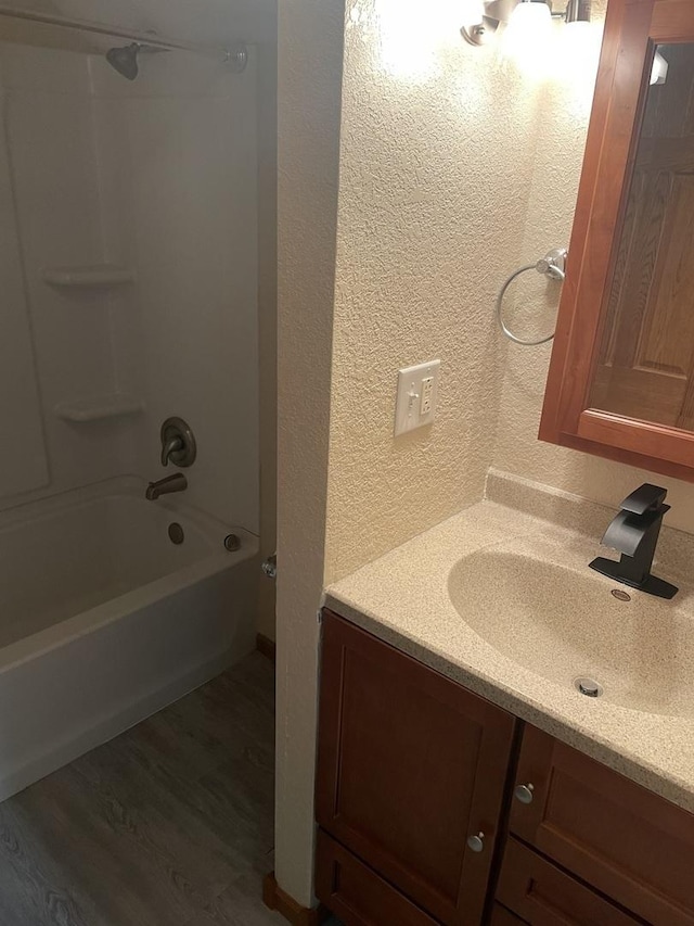 bathroom with hardwood / wood-style floors, vanity, and tub / shower combination