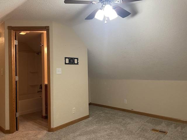 bonus room featuring a textured ceiling, ceiling fan, light colored carpet, and lofted ceiling