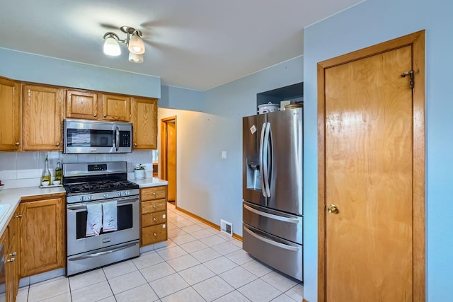 kitchen with light tile patterned floors, backsplash, and stainless steel appliances